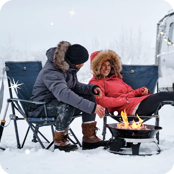 Two people sitting next to a bonfire in roadtrip rocker chairs. 