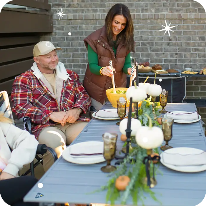 A woman serving her guests food on a slim-fold table. 