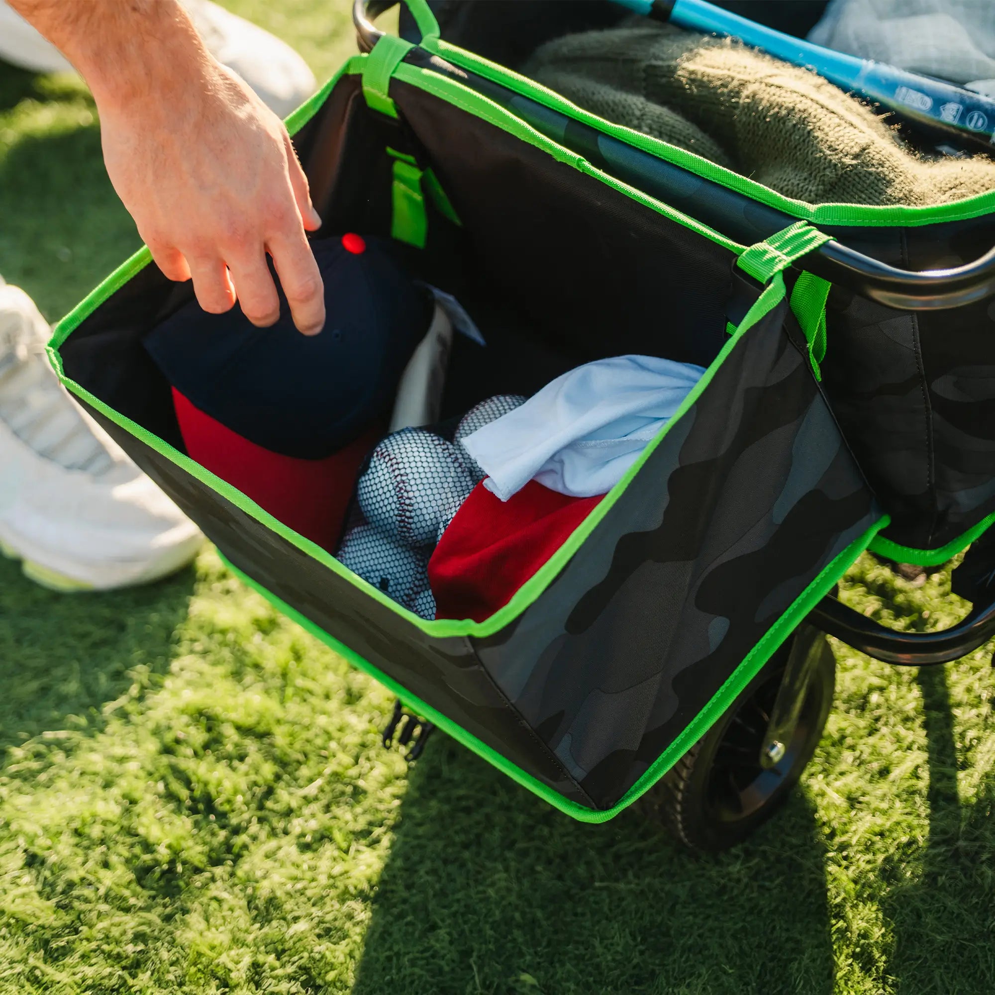 A person reaching into the go-hauler bumper caddy to grab baseball equipment. 