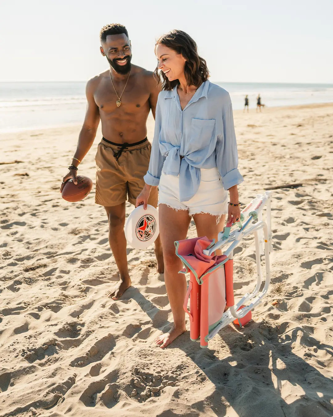 A couple walking together on a beach while a woman carries a pink Grab & Go Rocker. 
