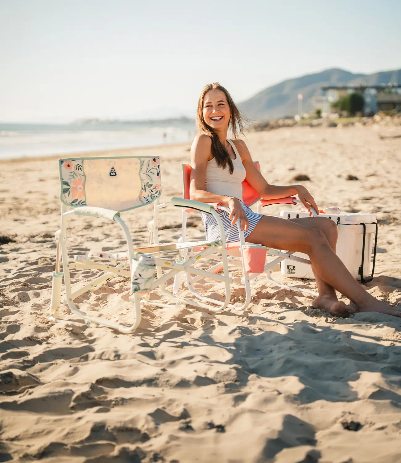 A woman sitting in a grab and go rocker while enjoying the beach. 