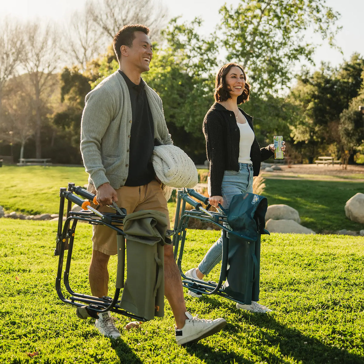 A couple walking at a park while carrying two Grab and Go Rockers. 