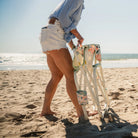 A woman unfolding a floral bouqet Grab & Go Rocker on a beach. 