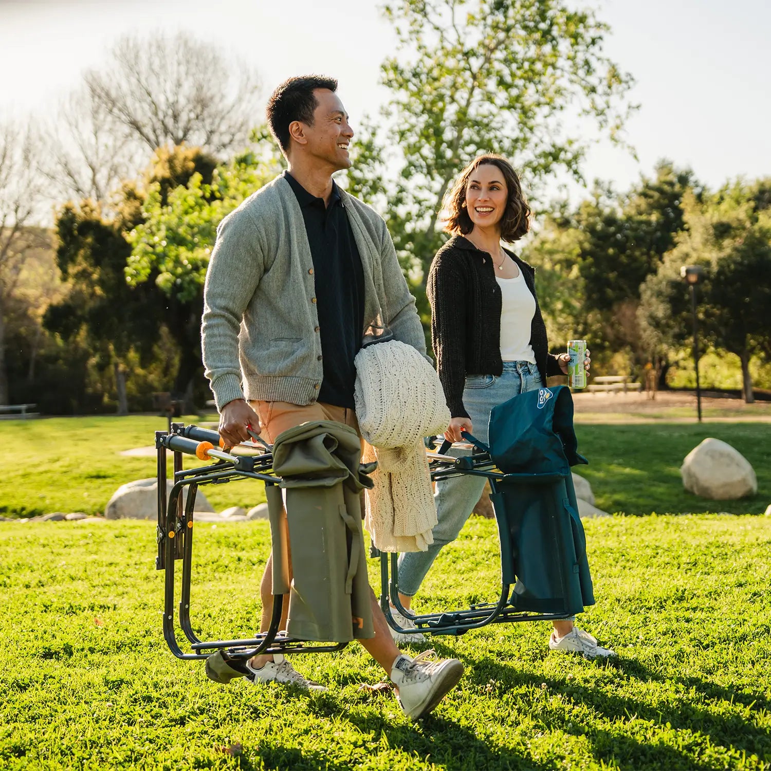 A couple walking at a park while carrying two Grab and Go Rockers. 