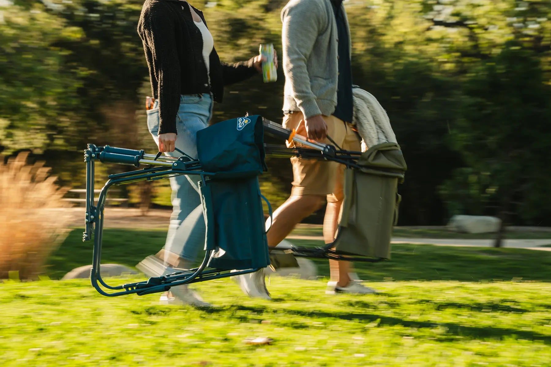 Two people actively walking in a park as they carry Grab and Go Rockers. 