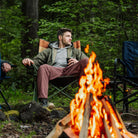 A man sitting in an Insulated Comfort Pro Rocker while sitting next to a bonfire. 
