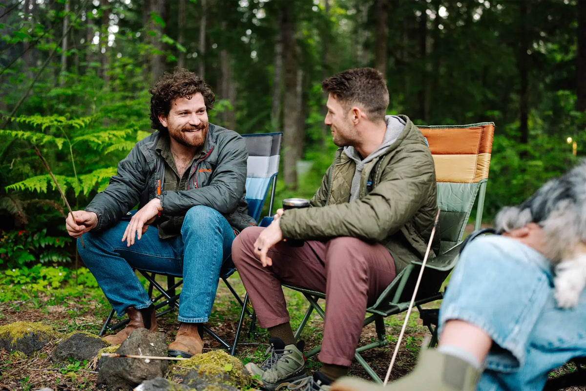 Two men sitting by a bonfire while sitting in two Insulated Comfort Pro Rockers. 