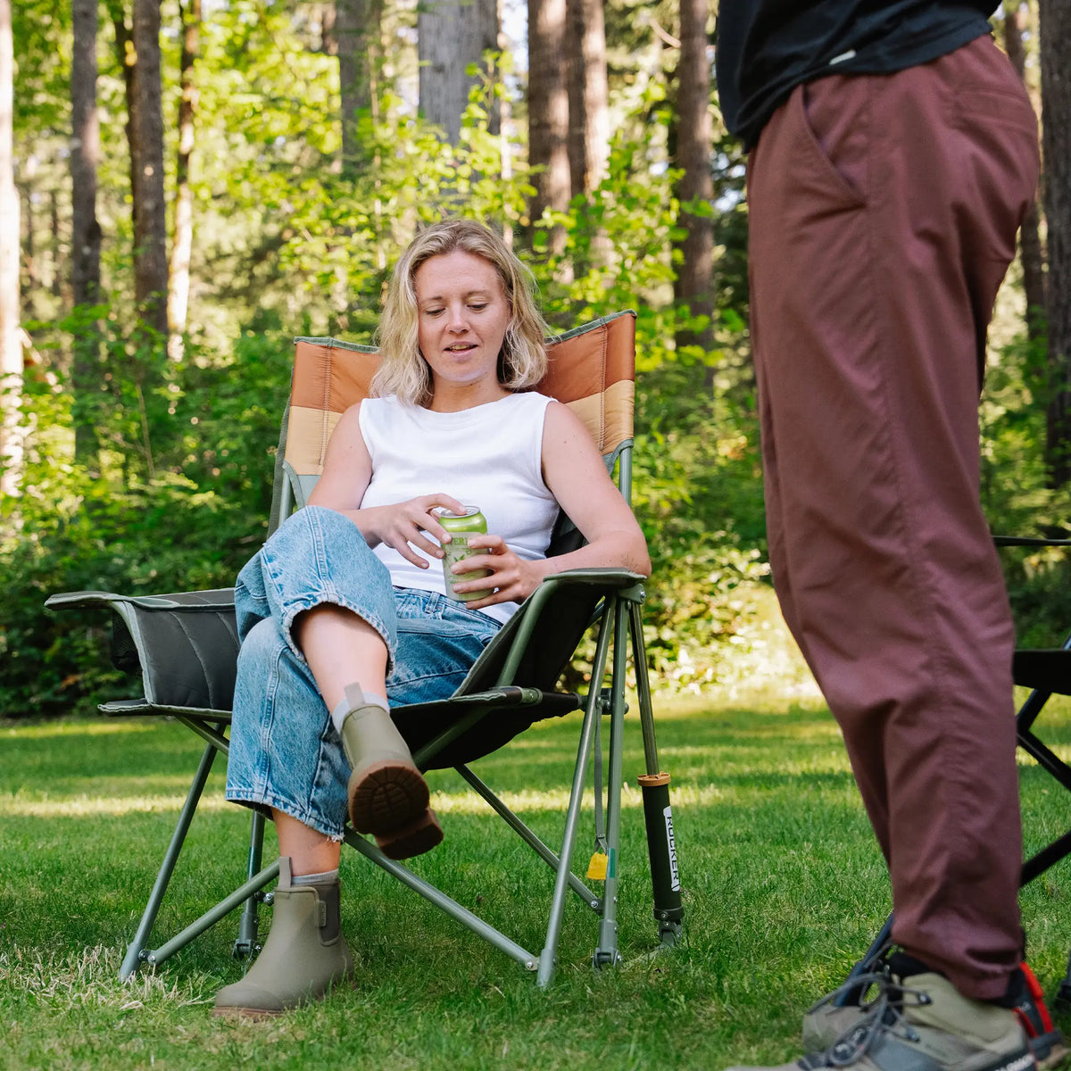 A woman opening a drink as she sits in an Insulated Comfort Pro Rocker. 