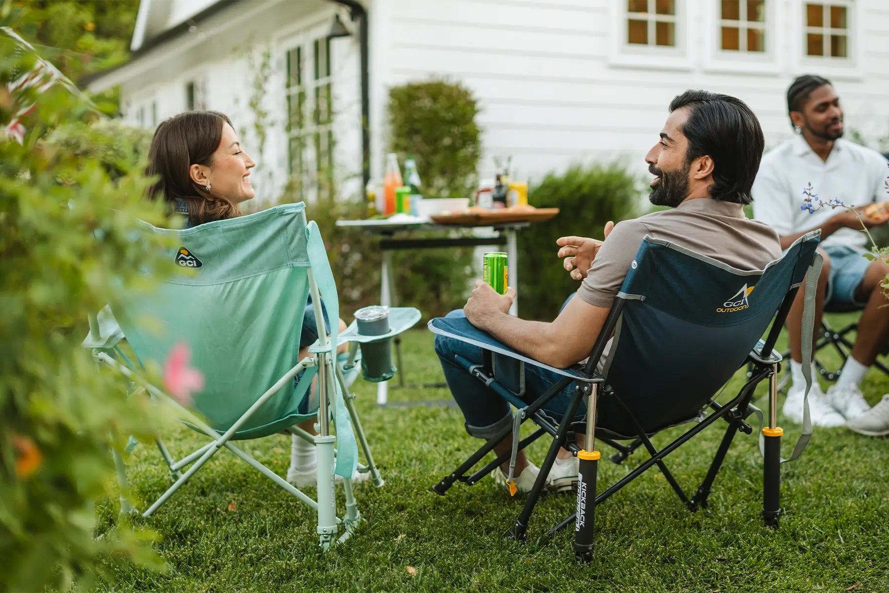 A couple sitting in kickback rocker chairs in a backyard setting. 