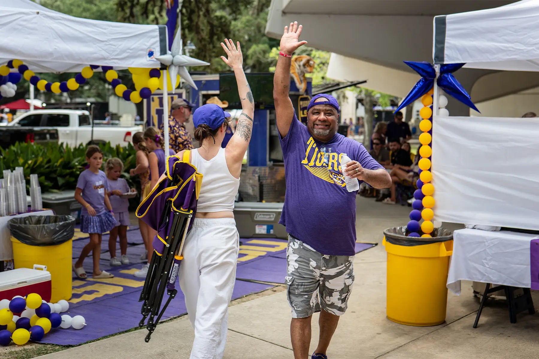 Two LSU fans high fiving one another at a tailgate party. 