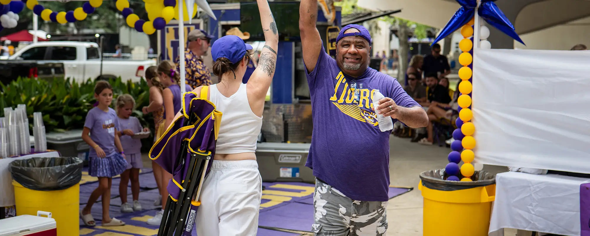 Two LSU fans high fiving one another at a tailgate party. 