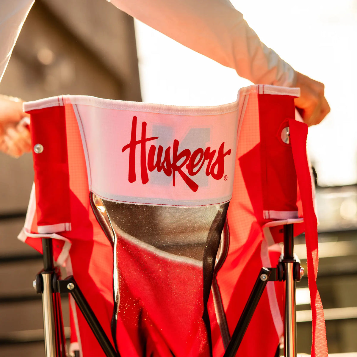 A person collapsing the nebraska cornhusker comfort pro rocker chair. 