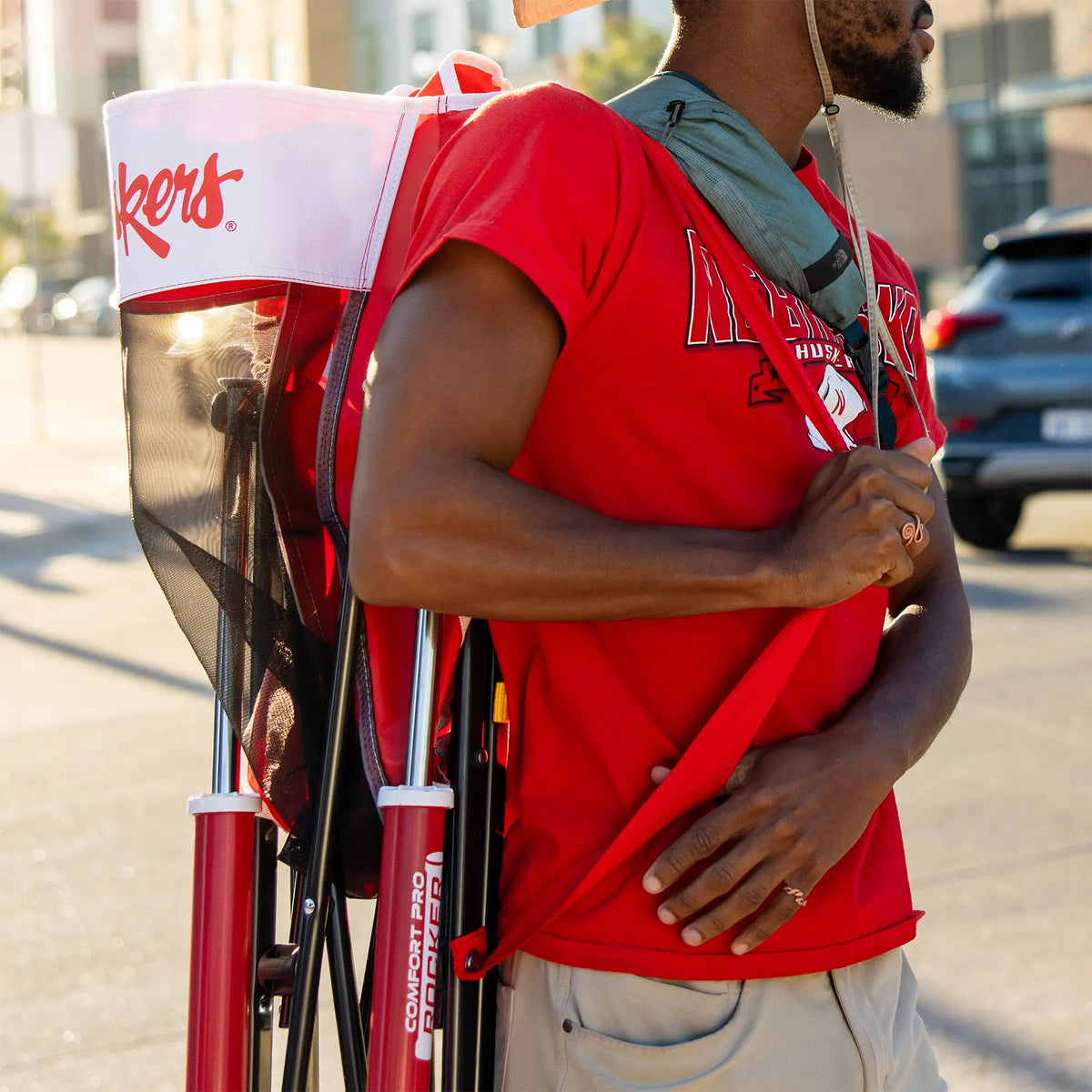 A man walking with a nebraska corn husker comfort pro rocker on his shouler. 