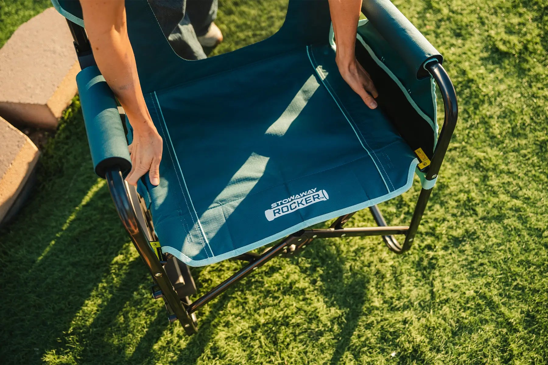 The teal Stowaway Rocker with Side Table being unfolded. 