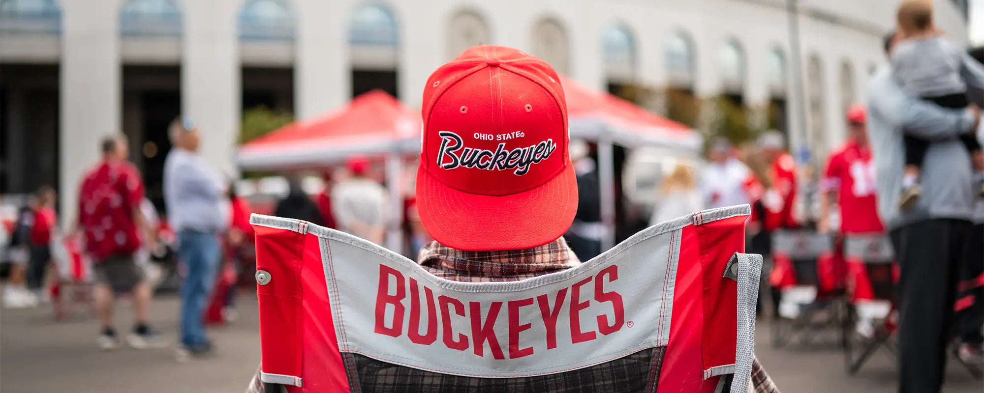 A man in an Ohio State Buckeyes hat sitting in an Ohio State Buckeyes Comfort Pro Rocker. 