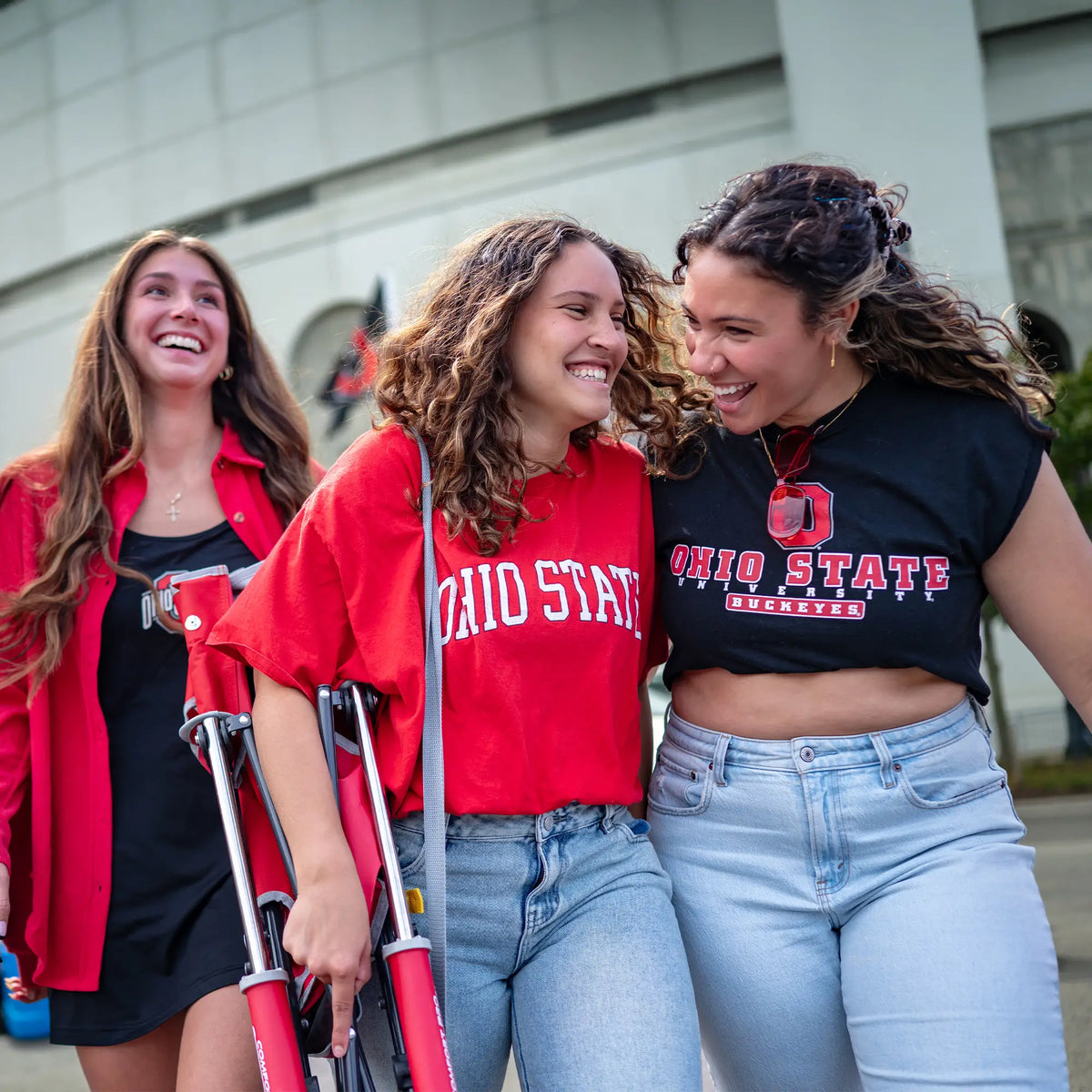A group of women walking away from the ohio state football stadium with the ohio state comfort pro rocker on a womans shoulder. 