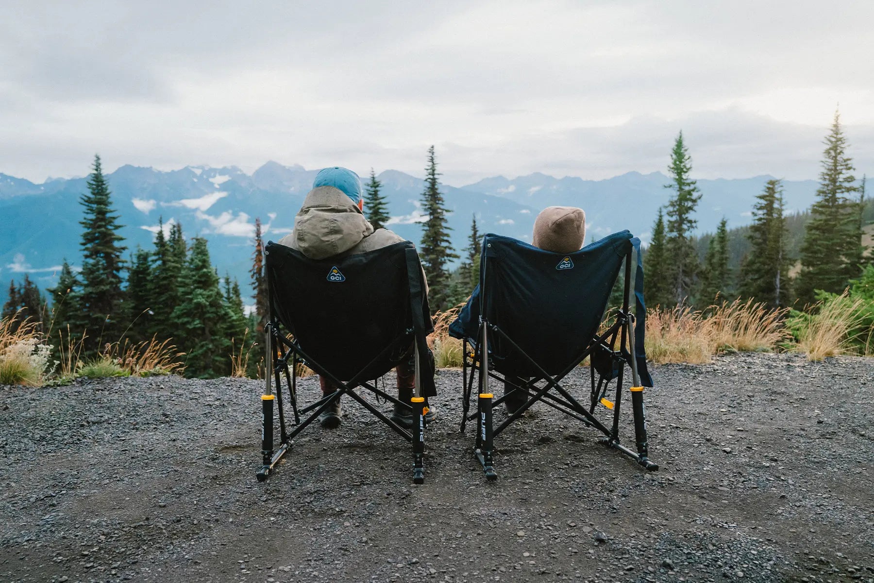 A couple observing a mountainous overlook while sitting in two Puff Rocker chairs. 