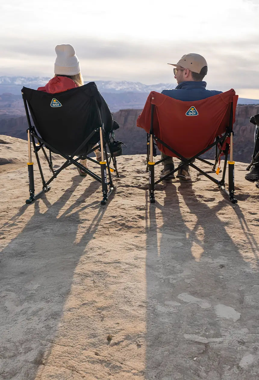 A couple sitting near a mountain cliff taking in the view on their puff rocker chairs. 
