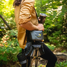 Person carrying a compact black Quik-E-Seat stool with shoulder strap.