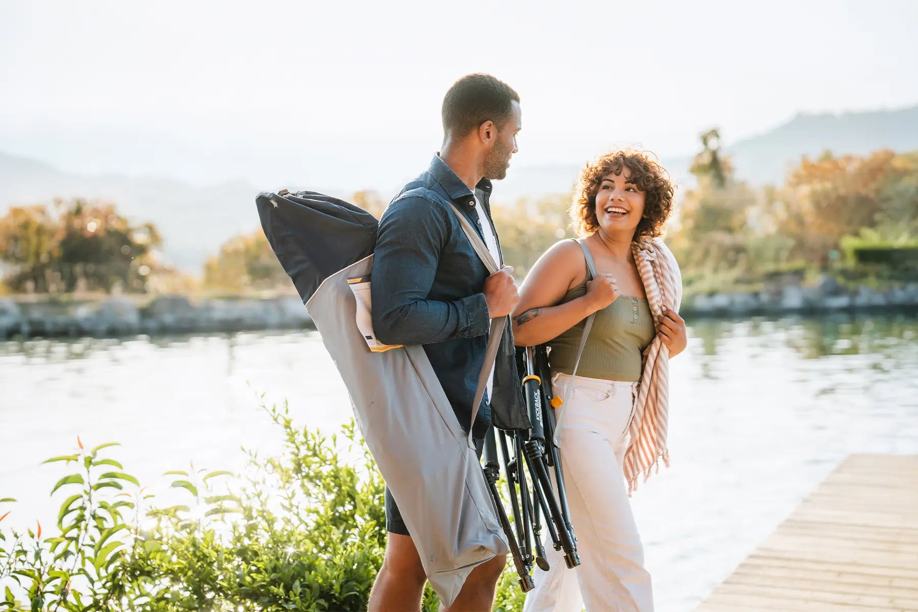 A couple walking near a body of water while holding the Roadtrip Rockers on their shoulders.