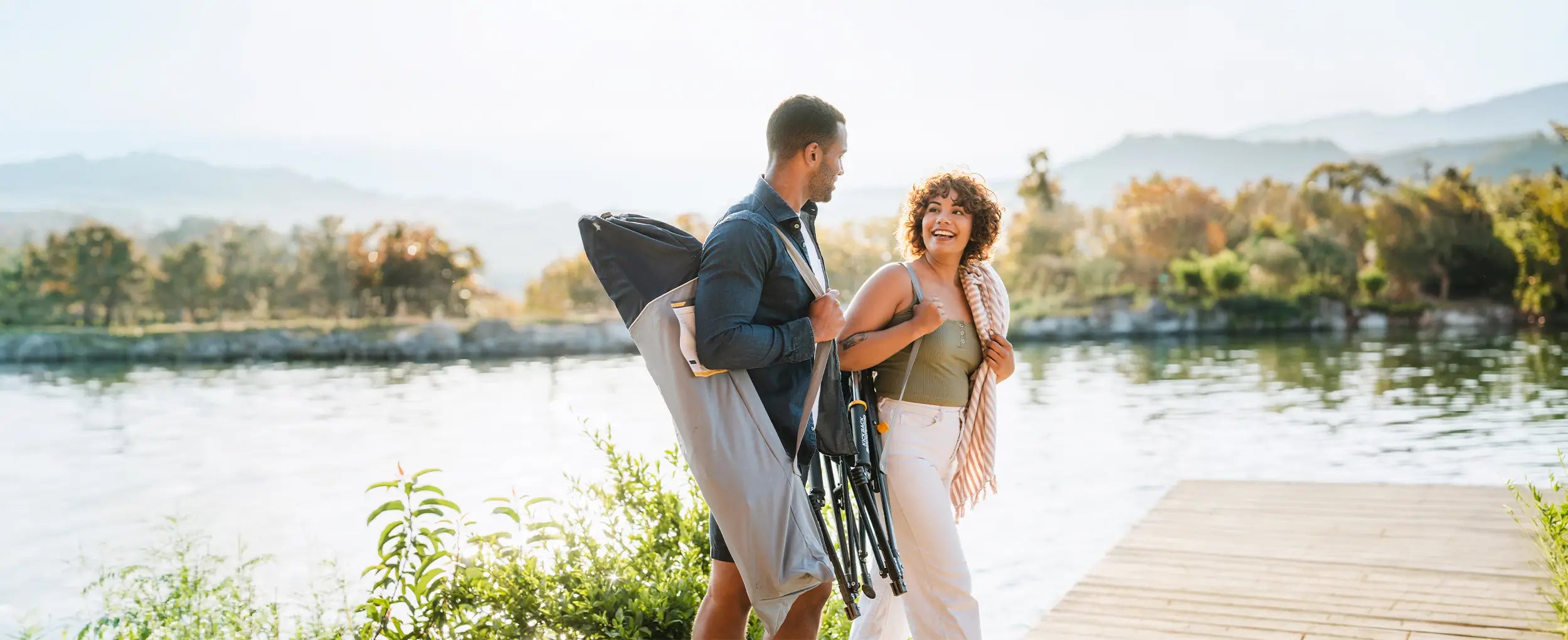 A couple walking near a body of water while holding the Roadtrip Rockers on their shoulders.