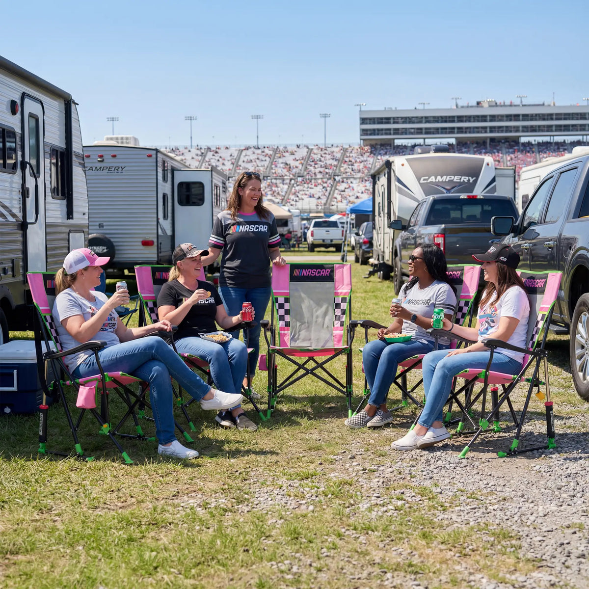 A group of NASCAR fans sitting on the racetrack with their pink NASCAR Roadtrip Rocker chairs. 