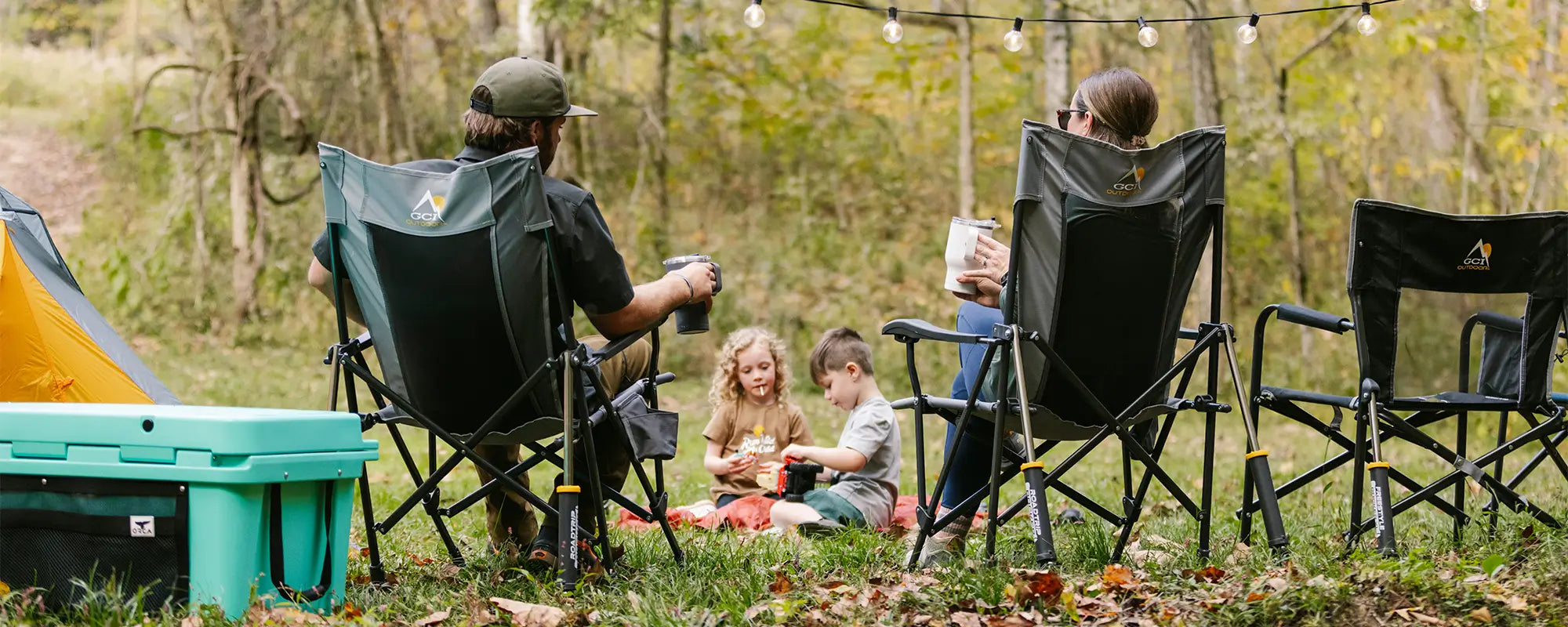 A couple sitting watching their kids play on a blanket while sitting in their roadtrip rocker chairs. 