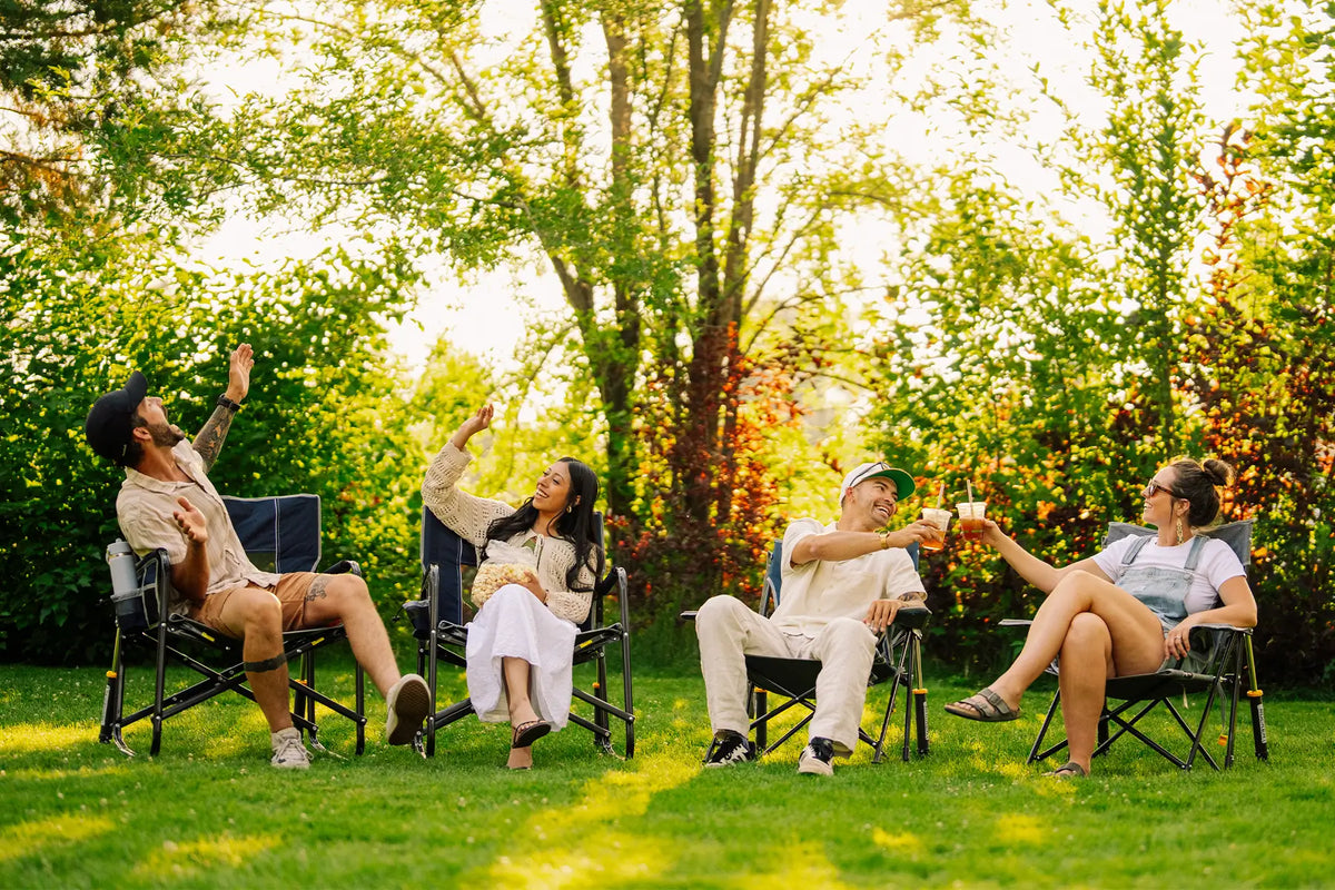 A group of friends sitting in a grassy area sitting in their GCI Outdoor Rockers. 
