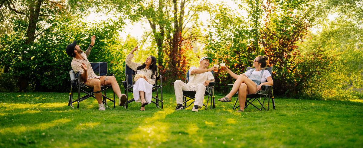 A group of friends sitting in a grassy area sitting in their GCI Outdoor Rockers. 