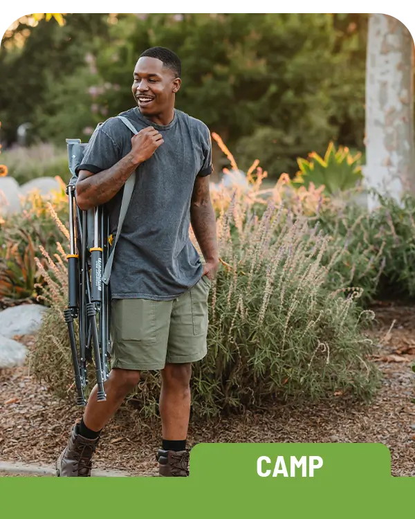 A man walking on a paved path as he carries a Roadtrip Rocker on his shoulders. 