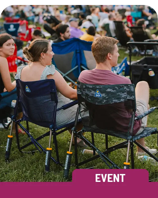 A couple sitting in two Freestyle Rocker Elite chairs at a concert venue. 