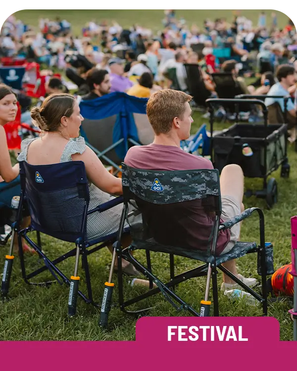 Two people sitting in freestyle rocker elite chairs at a concert venue. 