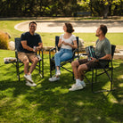 A group of people sitting at a park in their Slim-Fold Directors Chair XL. 