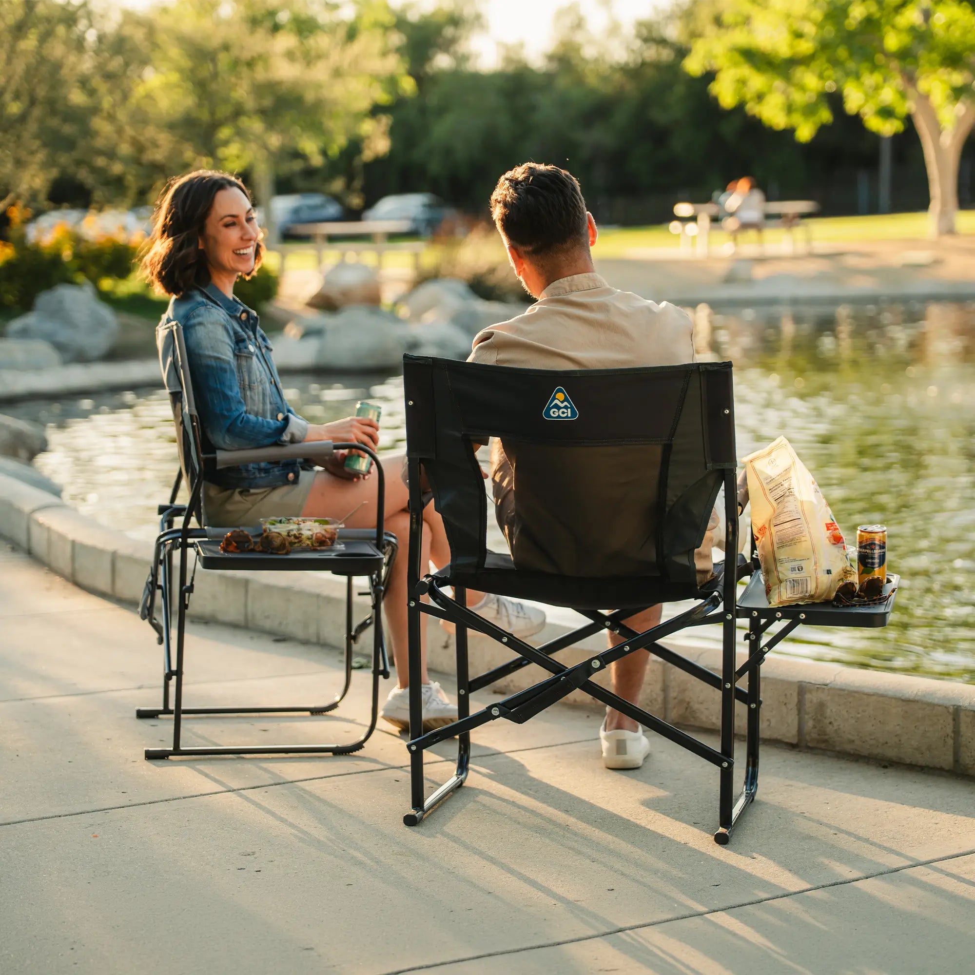 A couple sitting at a park in their Slim-Fold Directors Chair XL. 