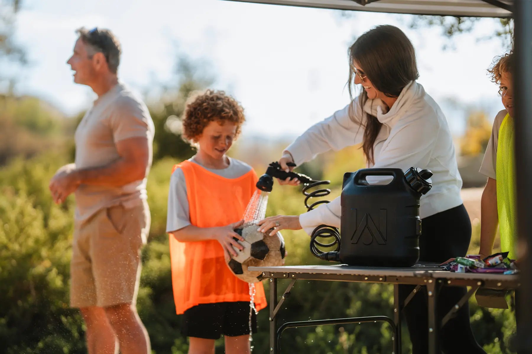 A woman washing off a childs soccer ball with a WaterPORT pressurized tank. 