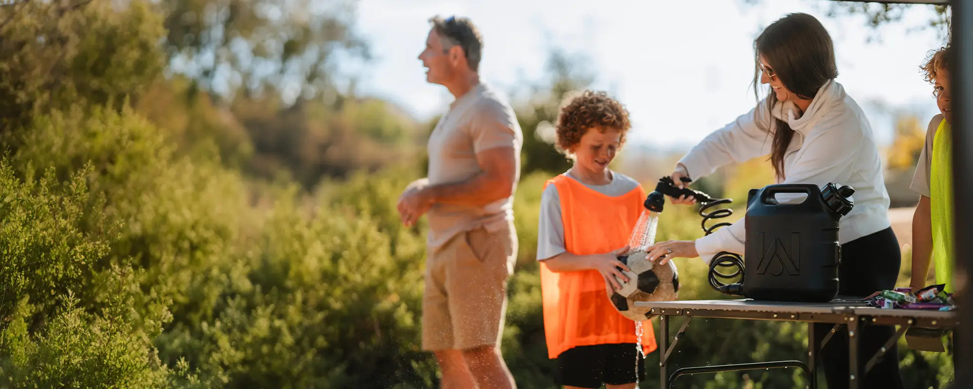 A woman washing off a childs soccer ball with a WaterPORT pressurized tank. 