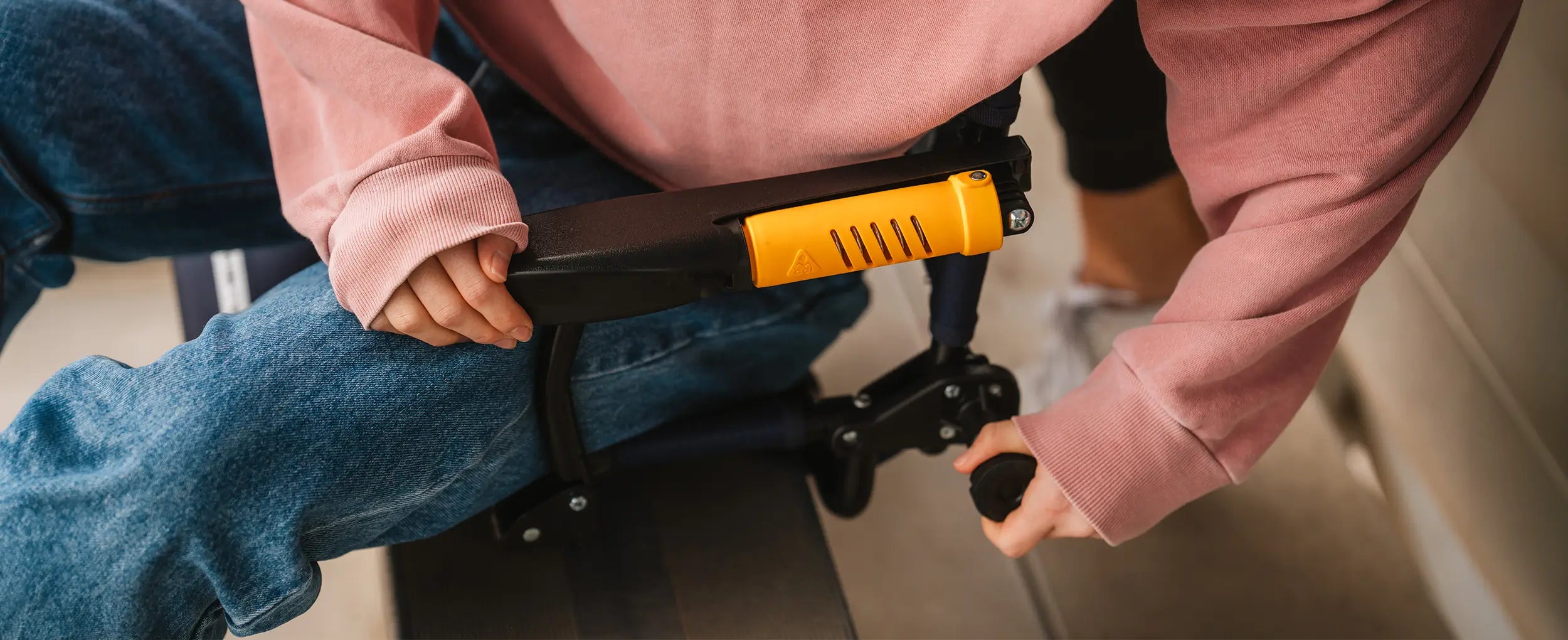 A woman adjusting the tension on her Stadium Rock-cliner chair while sitting on a bleacher. 
