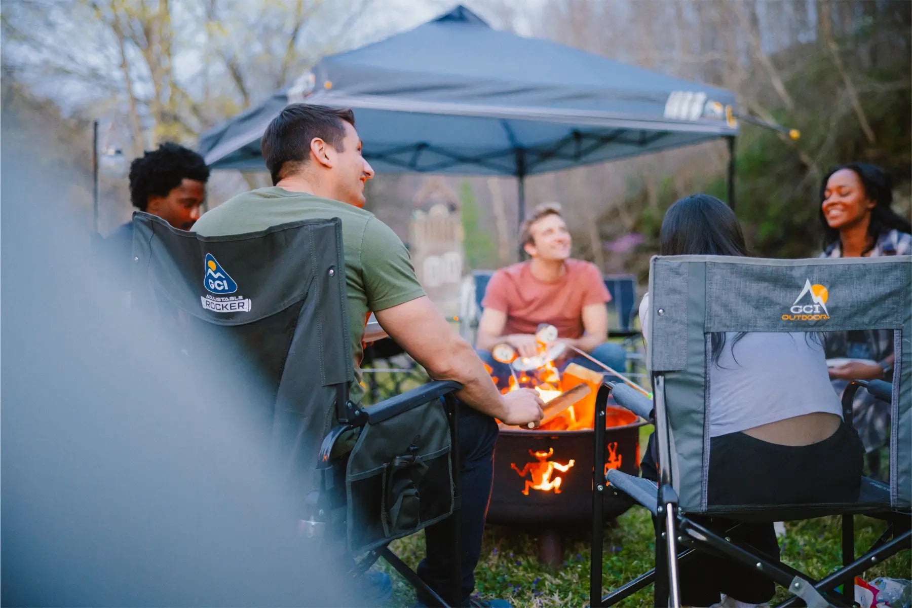 A group of people sitting in GCI Outdoor chairs around a bonfire. 