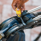 Hand pulling the yellow tab to unfold the Navy Topo Stowaway Rocker chair.