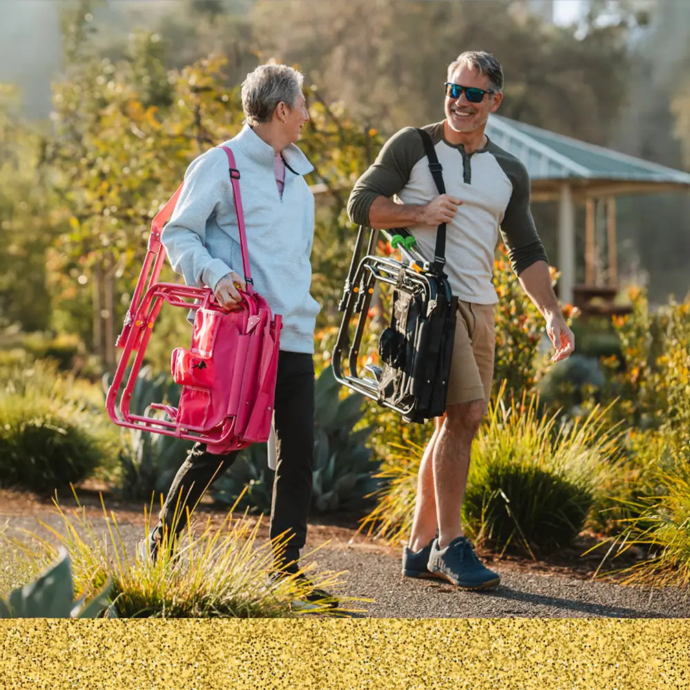 A couple walking on a paved path together while carrying their stowaway rocker with a shoulder strap. 