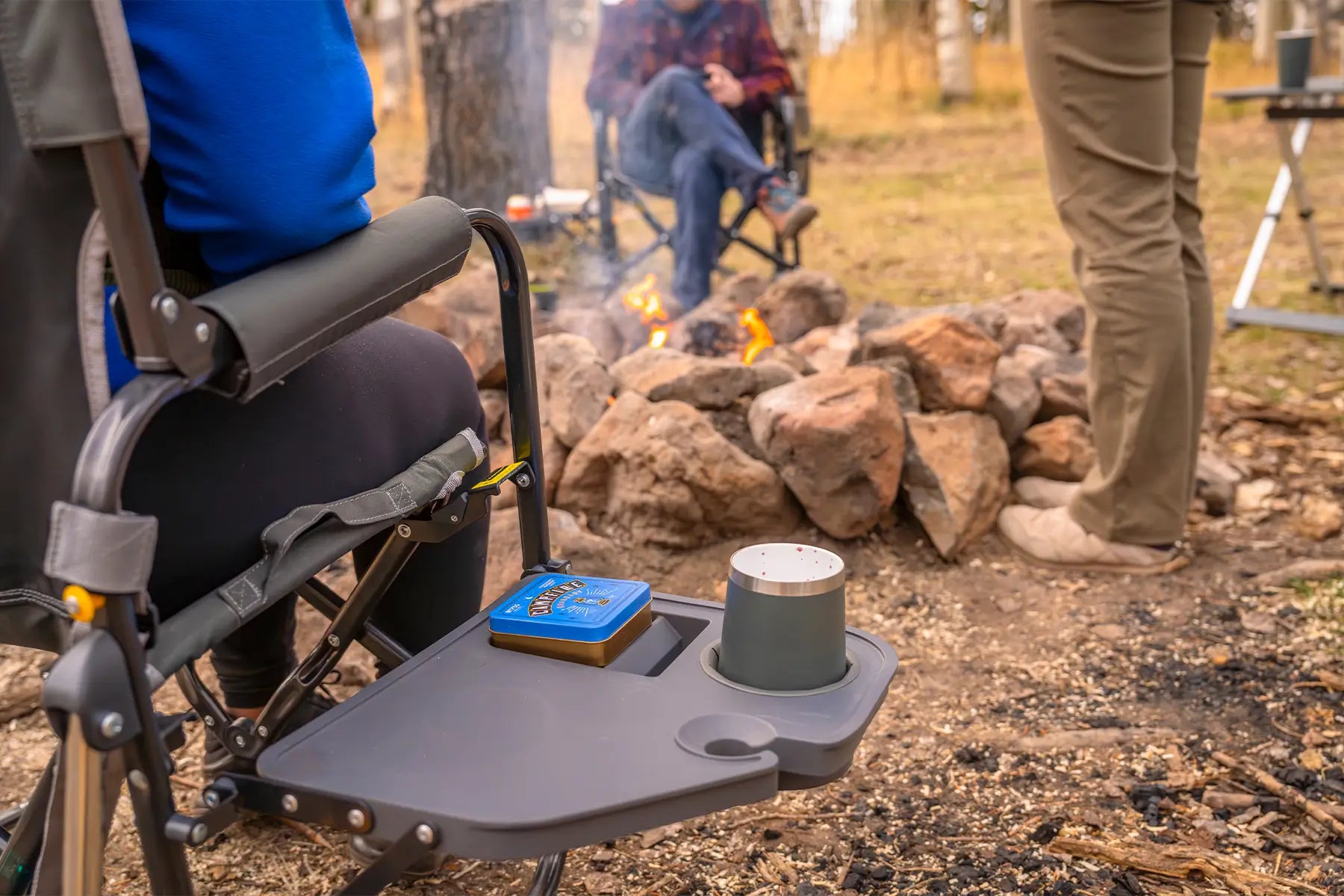 A tumbler and game resting on a Stowaway Rocker with Side Table at a campsite. 