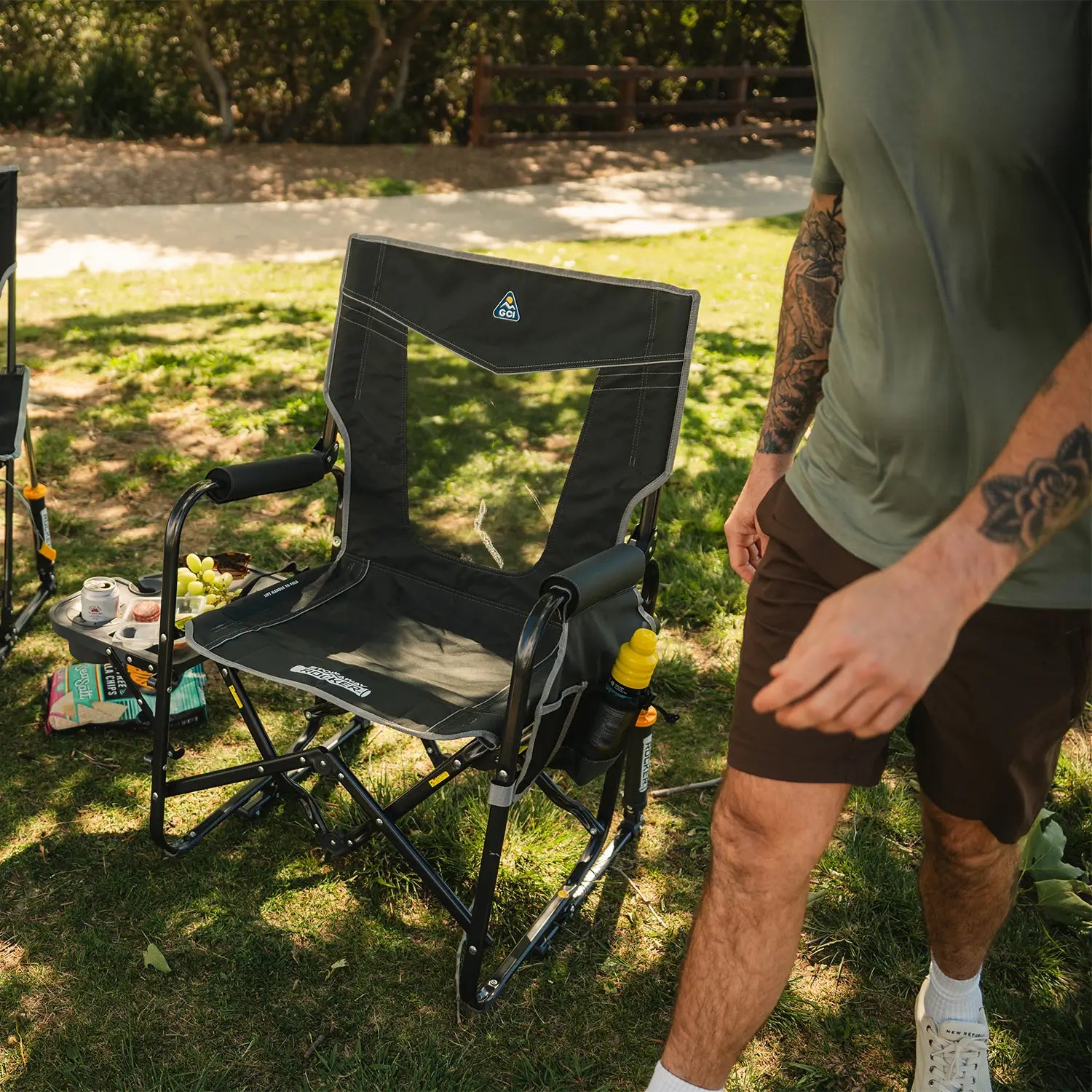 A full view of the black Stowaway Rocker with Side Table with a man walking towards the chair. 