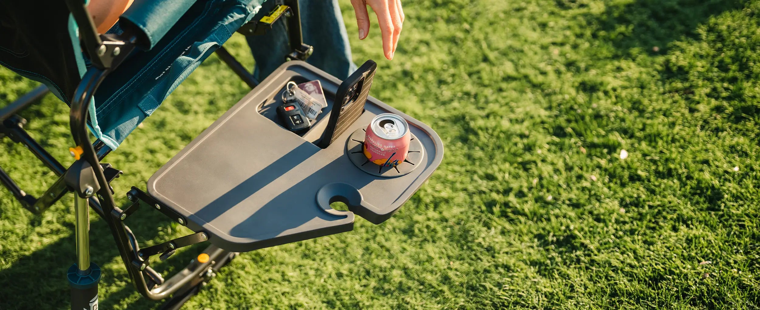 A person reaching for their phone that is positioned in the side table of the Stowaway Rocker with Side Table. 