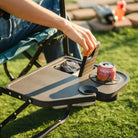 Close-up of the side table on the Teal Stowaway Rocker holding a drink and phone outdoors.