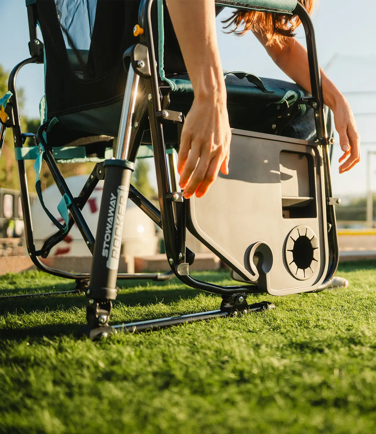 A woman unfolding the attached side table on the Stowaway Rocker with Side Table. 