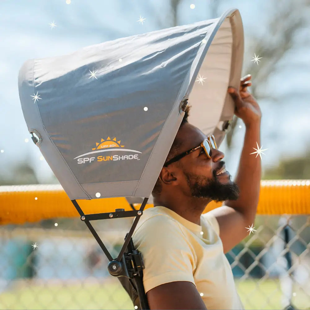 A man sitting in a GCI Outdoor chair positioning his sunshade accessory attached to the chair. 