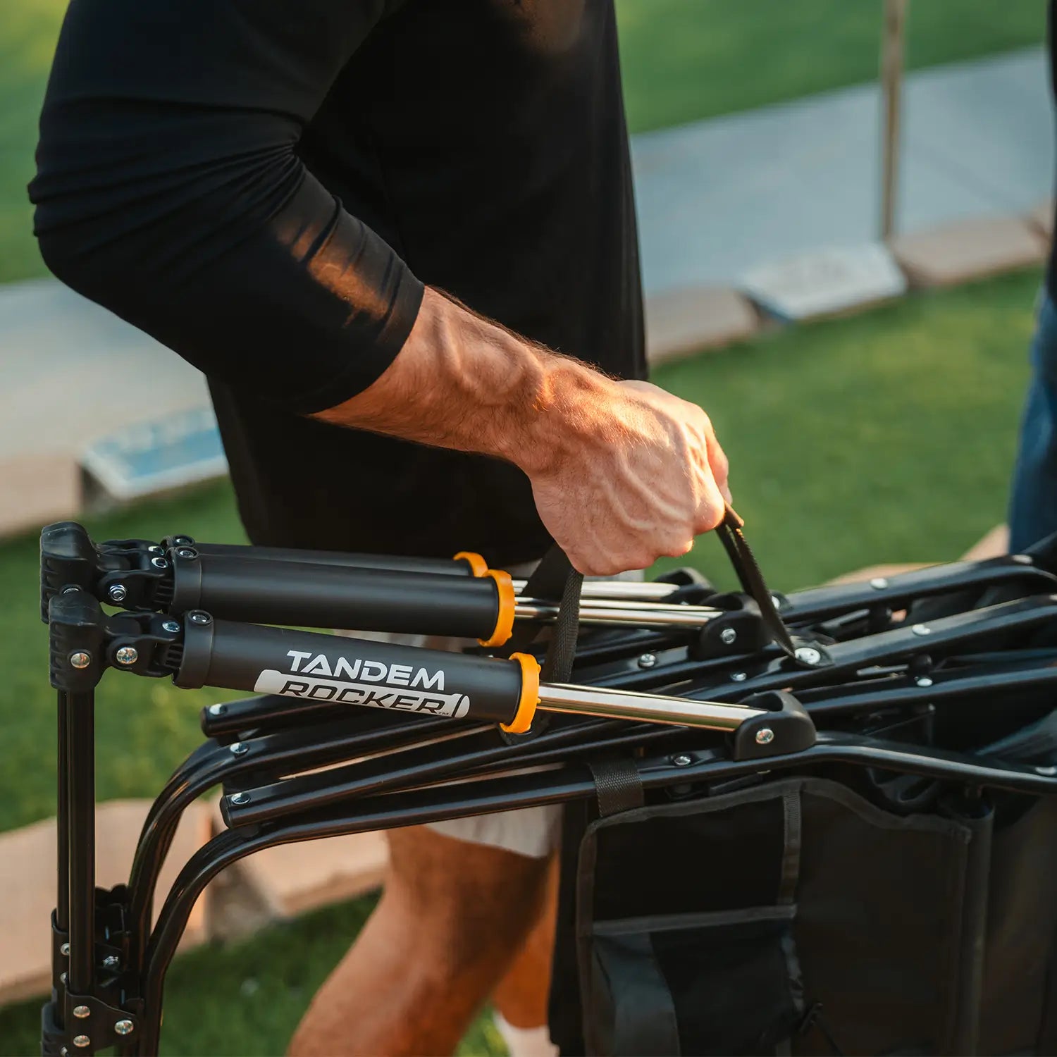A man using the attached carry handle on the Tandem Rocker to carry it across a field. 