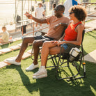 A couple sitting on a Tandem Rocker while watching a baseball game. 