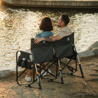 A couple sitting near a pond as they rock together on the Tandem Rocker. 