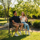 A couple sitting together on a Tandem Rocker while at a park. 